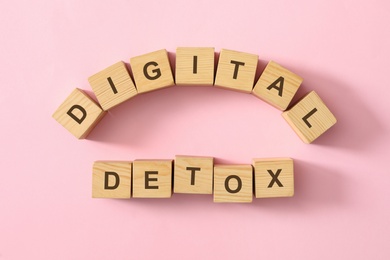 Photo of Wooden cubes with phrase DIGITAL DETOX on pink background, flat lay