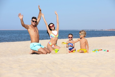 Happy family playing on sandy beach near sea. Summer holidays