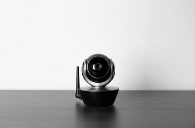 Baby monitor on wooden table against white background. CCTV equipment