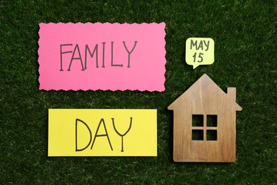 Photo of Cards with text Family Day and wooden house figure on green grass, flat lay