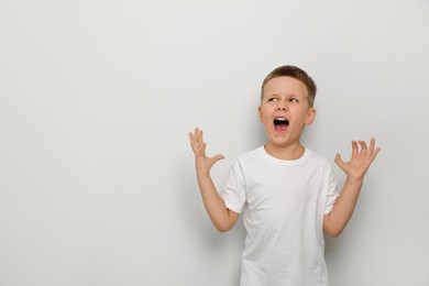 Photo of Angry little boy screaming on white background, space for text. Aggressive behavior