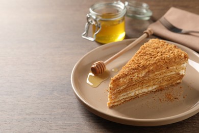 Slice of delicious layered honey cake served on wooden table. Space for text