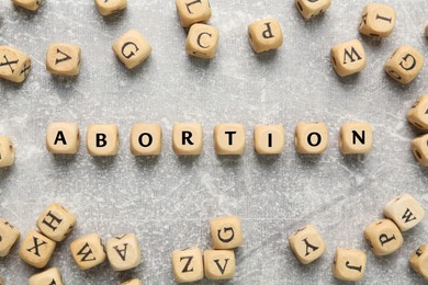 Word Abortion made of wooden cubes on grey background, flat lay