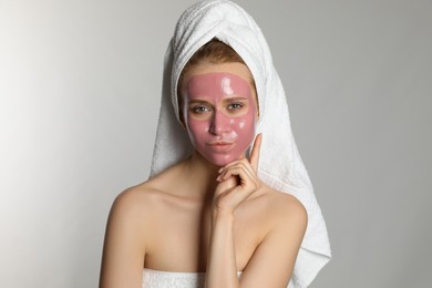 Photo of Young woman with pomegranate face mask on light grey background