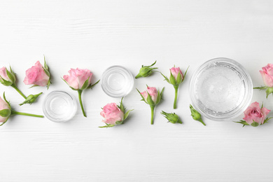 Flat lay composition with cosmetic gel and beautiful flowers on white wooden table