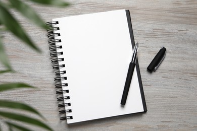 Open blank notebook and pen on light wooden table, flat lay