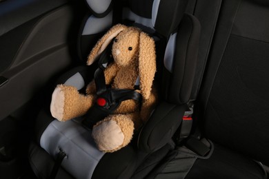 Toy bunny in child safety seat inside car
