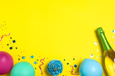 Flat lay composition with birthday decor and bottle of sparkling wine on yellow background, space for text