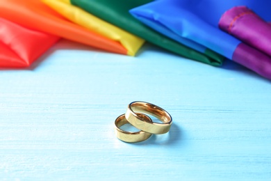 Wedding rings and rainbow flag on wooden table. Gay marriage