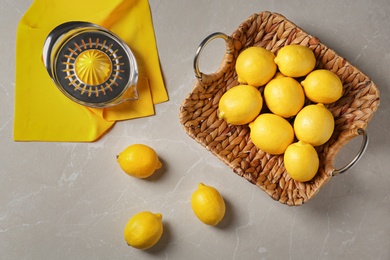 Flat lay composition with ripe lemons and juicer on gray table