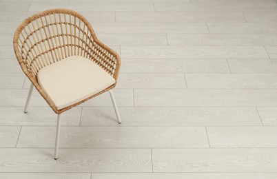 Stylish wicker armchair on floor. Space for text