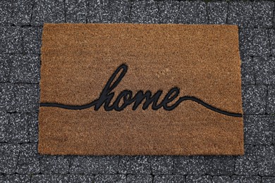 Photo of Doormat with word Home on pavement, top view