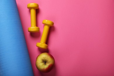 Photo of Fitness mat, dumbbells and apple on pink background, flat lay with space for text. Morning exercise