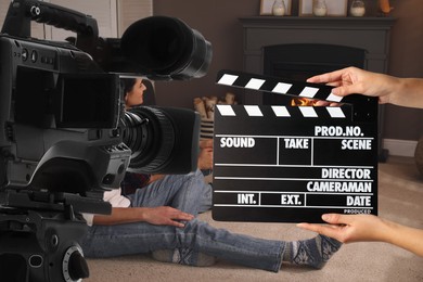 Image of Shooting movie. Second assistant camera holding clapperboard near video camera in front of couple (actors) in room with fireplace (film set)
