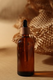 Photo of Glass bottle of cosmetic product on dark beige background