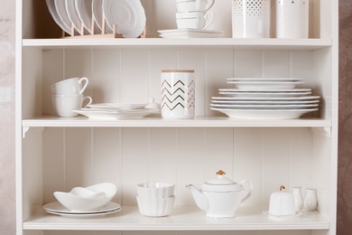 Stylish storage stand with different ceramic dishware at home