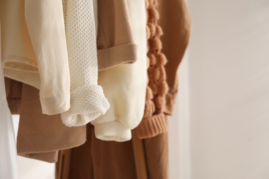 Rack with stylish women's clothes indoors, closeup. Modern interior design