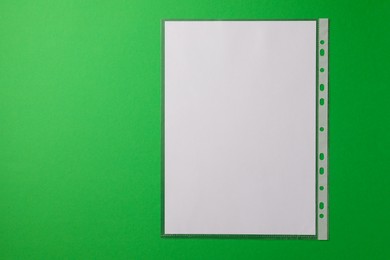 Photo of Punched pocket with paper sheet on green background, top view. Space for text