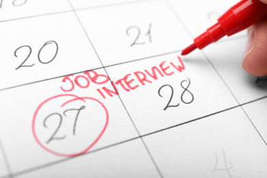 Woman marking date of job interview in calendar, closeup