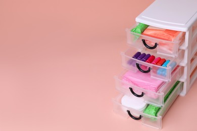 Plastic storage drawers with menstrual pads and tampons on pink background, closeup. Space for text