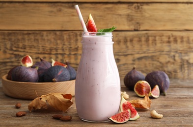 Delicious fig smoothie in glass bottle on wooden table