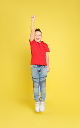 Cute little boy jumping on yellow background