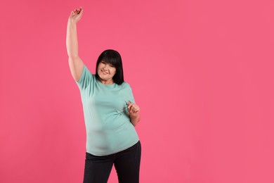 Beautiful overweight mature woman with charming smile on pink background. Space for text