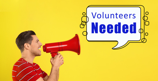 Young man with megaphone and text VOLUNTEERS NEEDED on yellow background