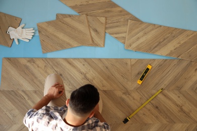 Professional worker installing new parquet flooring indoors, top view
