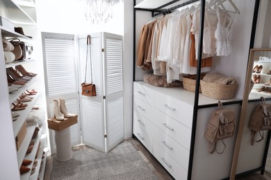 Photo of Dressing room interior with clothes rack and collection of stylish shoes