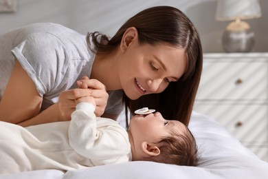 Photo of Happy mother with her little baby on bed at home