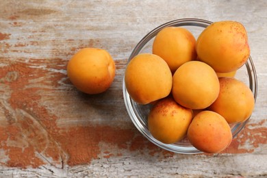 Glass bowl with delicious ripe apricots on wooden table, flat lay