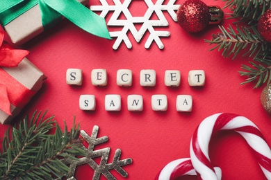 Flat lay composition with festive decor, presents and words Secret Santa on red background