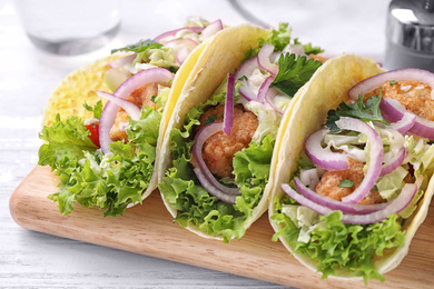 Photo of Yummy fish tacos served on white wooden table, closeup