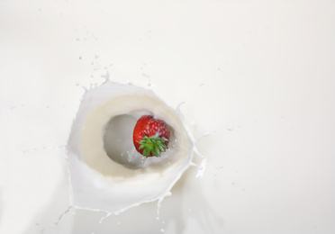 Strawberry falling in milk with splash, top view