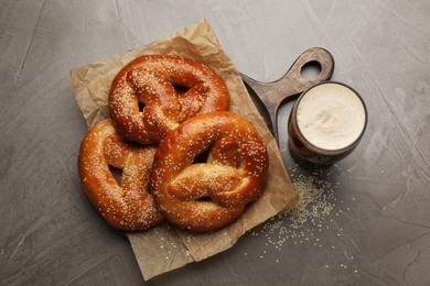 Tasty pretzels and glass of beer on grey table, flat lay