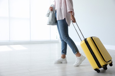 Woman with yellow travel suitcase in airport. Space for text