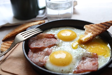 Tasty fried eggs with bacon and toast on table, closeup