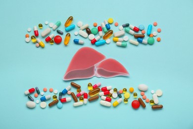 Photo of Paper liver and pills on turquoise background, flat lay. Hepatitis treatment