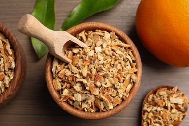 Photo of Bowl of dried orange zest seasoning and fresh fruit on wooden table, flat lay