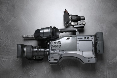 Modern video camera with flashlight on grey stone background, top view