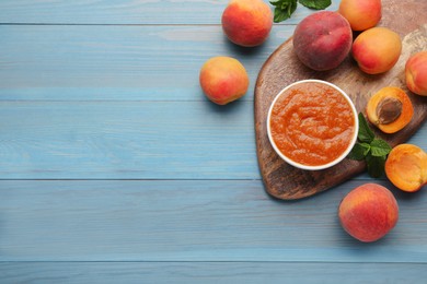 Photo of Apricot puree in bowl and fresh fruits on light blue wooden table, flat lay. Space for text
