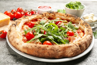 Tasty pizza with meat and arugula on grey table, closeup