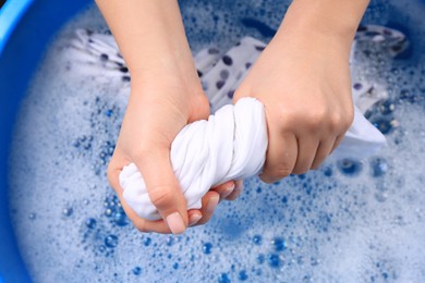 Woman wringing garment over basin, closeup. Hand washing laundry