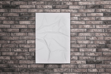 Blank creased poster on grey brick wall. Mockup for design 