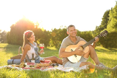 Happy couple with guitar on picnic in park