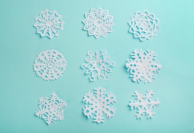 Flat lay composition with paper snowflakes on cyan background