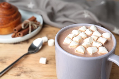 Delicious hot cocoa drink with marshmallows in cup on wooden table, closeup