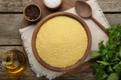 Photo of Raw couscous and ingredients on wooden table, flat lay