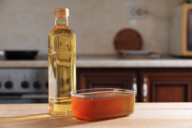 Photo of New and used cooking oil on wooden table in kitchen